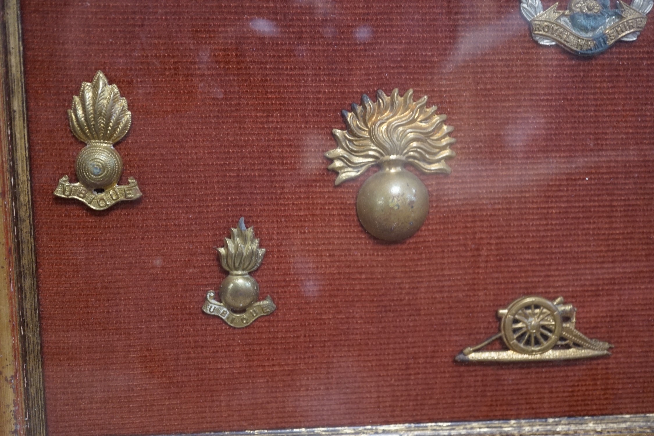 A framed collection of military cap Badges
